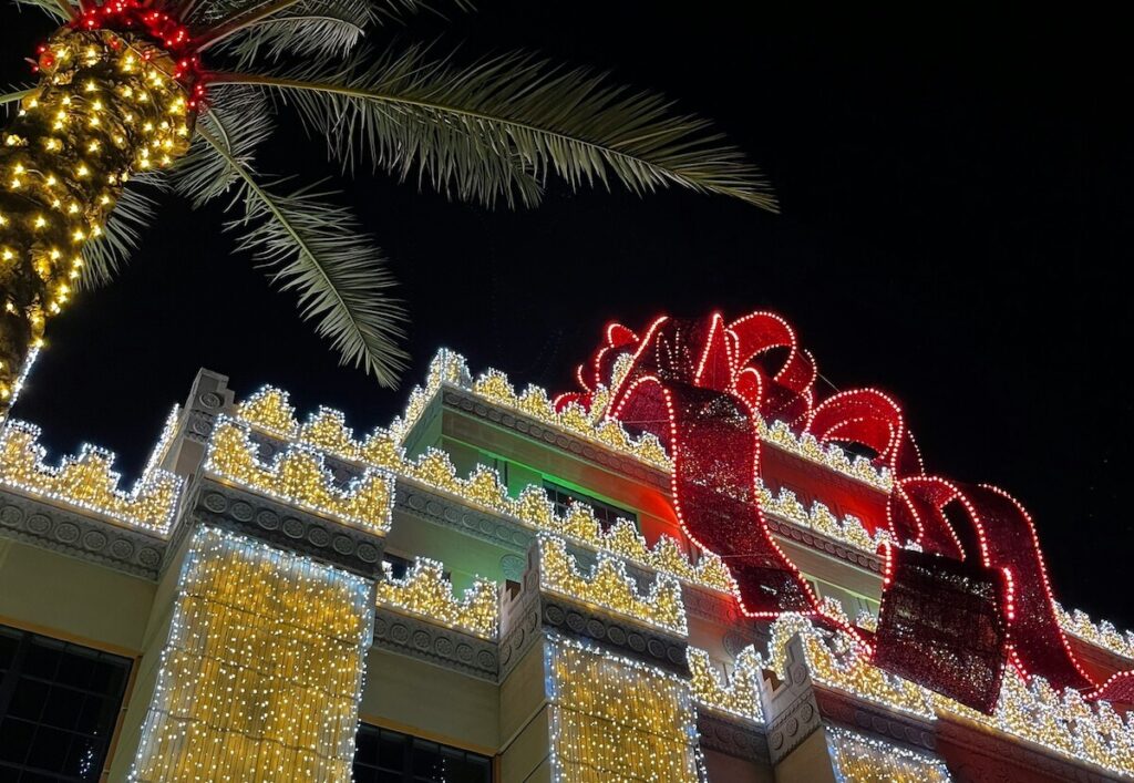 Kuala Lumpur luxury hotel exterior decorated with spectacular Christmas lights, festive decorations, illuminated entrance, and families arriving for holiday staycation