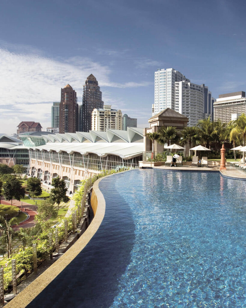 Alt text: Mandarin Oriental Kuala Lumpur resort-style pool with kids' pool area, tropical landscaping, sun loungers, and KLCC Park in background